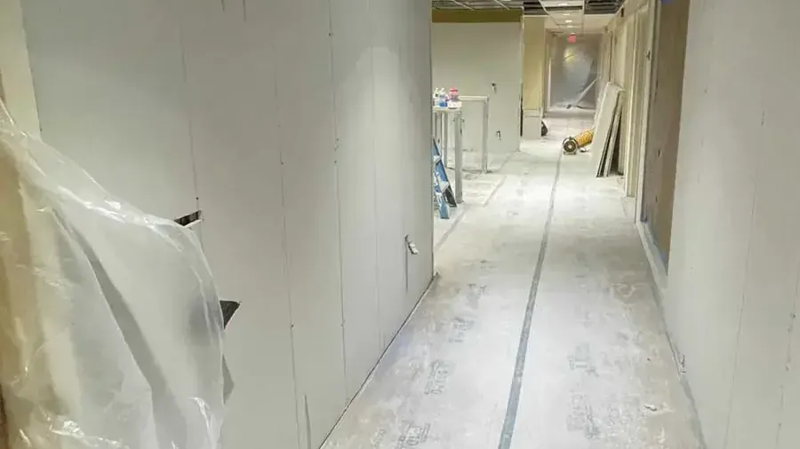 Plastic containment and opened wall bottoms along a hallway during structural drying