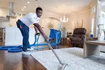 Technician running an extraction wand across a soaked rug in a living room